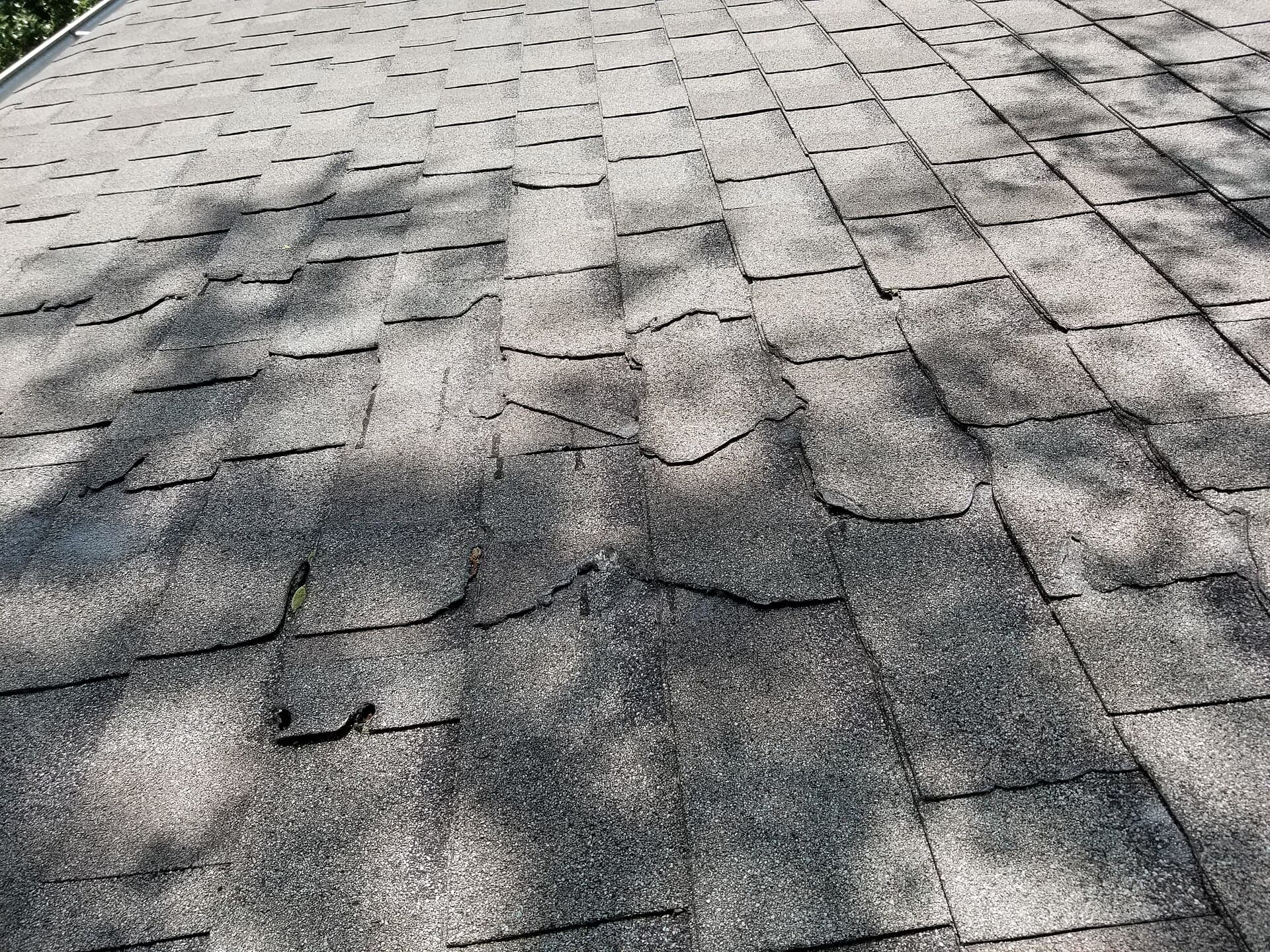 Storm-damaged grey shingles with a torn tab