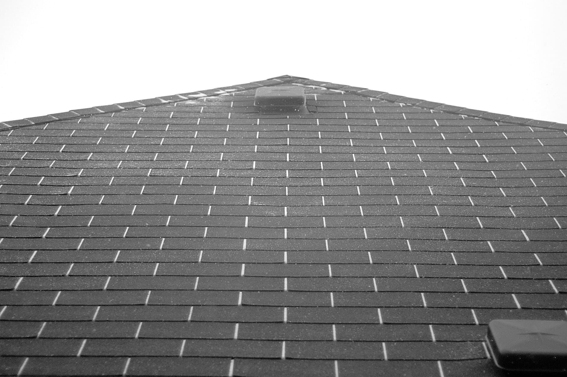 A grey shingle roof under a thin layer of snow